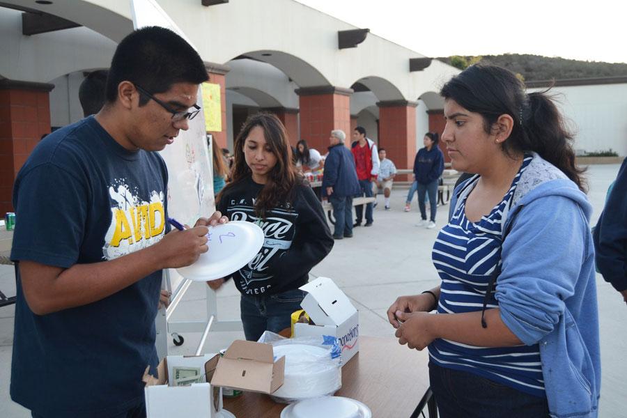 TACO MAN: AVID fundraiser sold tacos, $1 for an individual and $5 for a taco combo plate, at back to school night. Giovanny Menchaca (left) and Alondra Arcos (center) sold tacos to Gabriella Ramirez (right), and other customers, in order to raise money for AVID.