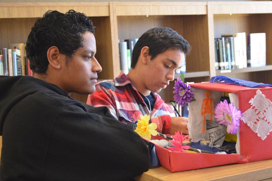 DAY OF THE DEAD: Sophomores Victor Rodriguez and Chris Gardea evaluate a Dia De Los Muertos project in the library. The project was a part of a Spanish class study of a holiday important to Latin American culture. Students made “altars” to either a deceased family member or to a pop culture icon. Students had to include items that were symbolic of the person’s life.  They were judged in the categories best overall, most creative and most sentimental value. 