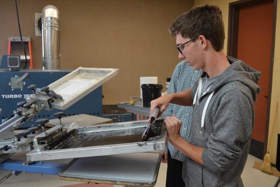 CREATIVITY FLOWS ONTO THE FABRIC: A student creates a T-shirt with a snappy design using the silkscreen press machine to print the design onto the fabric. Mr. Carlson assigns many projects to students that include making T-shirts and the student may keep the T-shirt after the process. File photo 