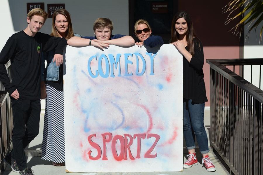 (From left to right) Comedy Sportz co-Captain Jay Tretter (12), advisor Jennifer Wooten, co-captain Ian Happy (11), advisor Kathy Boggio, and manager Kali Hoffman (12) strike a pose with their colorful, but not too colorful, sign. 
