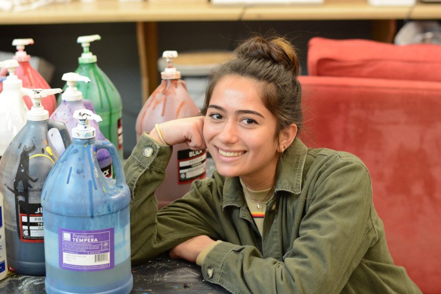 Artist Alison Miranda poses in the AP Studio Art room beside jugs of acrylic paint. The new class has been widely popular with the student body and will likely continue.