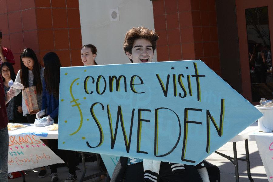 A member from the “3D Club” encourages students to come visit their club’s table.  The 3D Club had food and decorations from Sweden.