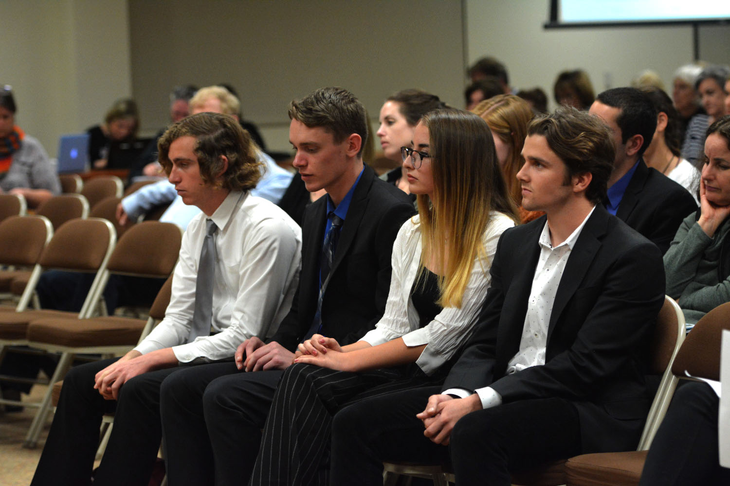 From left to right: Jack Hartstein (12), Kyle Krueger (12), Ava Bachelder (11), and Jackson Hinkle (12), watch as their peers speak in favor of the new gun control resolution. The resolution passed 4-3.