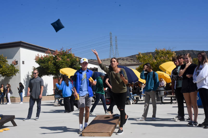  Nicole Haghani (11) throws a beanbag during her cornhole match on October 17 as her partner Luke Whittaker (11) and spectators watch. The annual cornhole tournament happened during lunch everyday this week, and teachers Matt Ahmer and Damon Garner won.