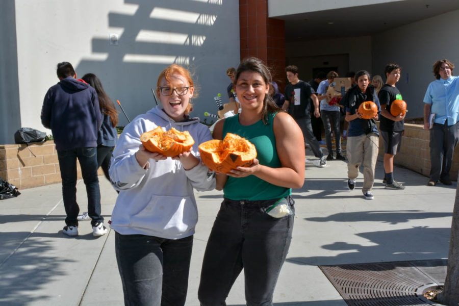 Taylor Hilton (11) and Isabelle Cota (10) hold their pumpkin after dropping it from the top of the upper quad for their physics class. “It’s a project where we try to protect a pumpkin from cracking by dropping it off a roof in a structure made from almost everything-- except packing peanuts,” said Cota. Hilton and Cota had been working on their projects for a couple of weeks.