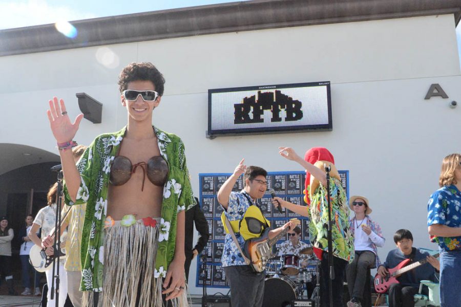 Day 3 The Hawaiian Band: Sebastian Miletich (10) acts as a security guard for the hawaiian band during their performance. The performance included a showcase of unique attire, including a hot dog costume from singer Grant Haliburton (11) and a sunglass emoji costume from guitarist Jermey Yu.