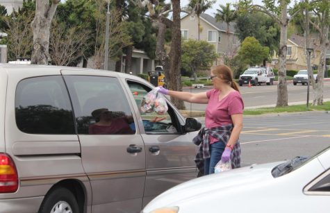 A volunteer for the drive-through lunch service hands a student a bag of food at Marco Forester Middle School. For the next three weeks, breakfast and lunch will be available at various elementary and middle schools for any student due to school closure.