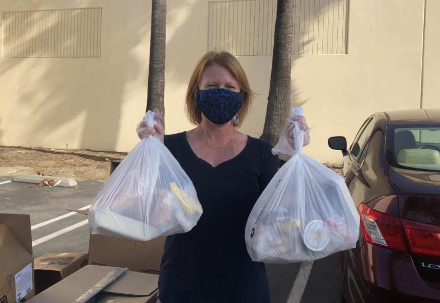 Kristin Hilleman, director of food and nutrition services of CUSD, smiles with under her mask as she holds food bags. These food bags are free for pickup at school for in person students or at the CUSD Food & Nutrition Services Office for online students. Any CUSD student can pick up these bags for free.