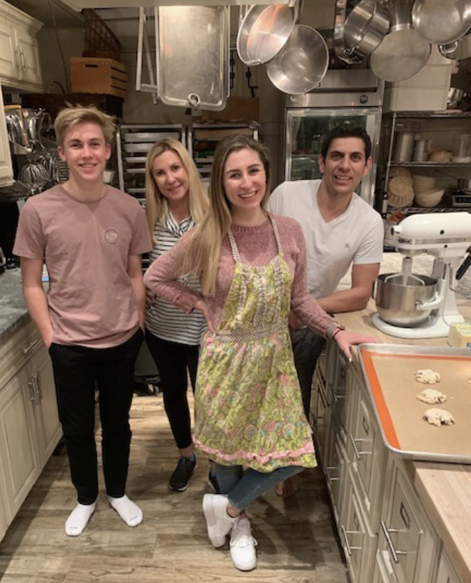 Christine and Victor Abuharoon, as well as two of their volunteers, Sofia and Jordan Votava, pose in the kitchen. While the main product is pizza dough, SMIJJ has recently began selling cookies, which can be seen on the cooking tray,