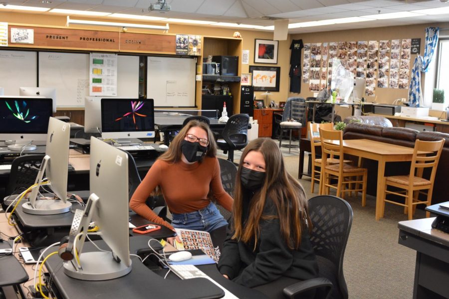 Students Jaycee Roberts (left) and Amelia Ray (right) pose while working on the yearbook during hybrid online schooling.