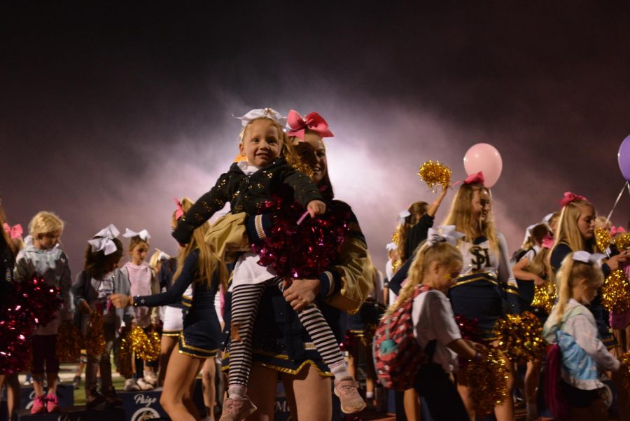 Cheerleader Kayla Todd holds a future stallion after participating in the halftime show. The game was future stallions night, where many parents and young children/middle schoolers flooded the stands. During the performance, both future and current stallion cheerleaders danced together.