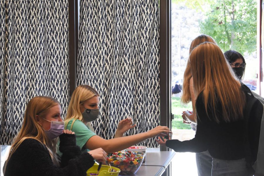 Seniors Macy Loren and Kendall Rogers greet freshmen at the door with candy during the Trick or Treat event. 