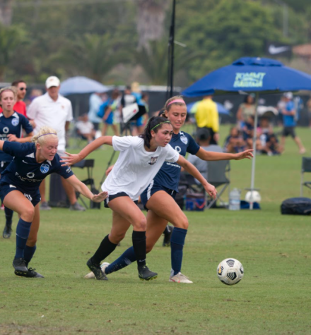 Student-athlete Cassidy Segrell (11) playing for her club soccer team, Strikers FC through a swarm of opposing players.