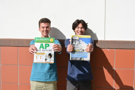 Book drive hosts Gavin Lynde (11) and Enzo Sarayba (11) hold up copies of donated books. Students are encouraged to donate any test prep books, from AP to SAT/ACT, until April 1. 
