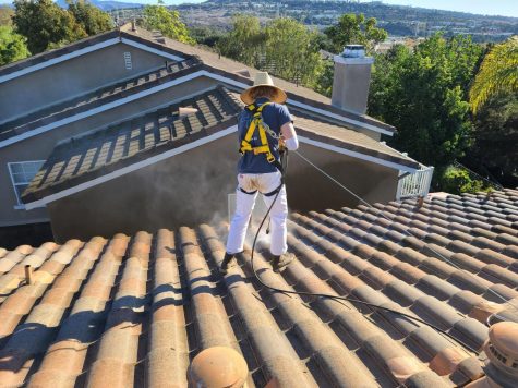 Entrepreneur Cruz Magee (12) pressure washes the roof of a local home in the community. Magee has turned a little neighborhood gig into a successful business, Triton Cleaning Services.