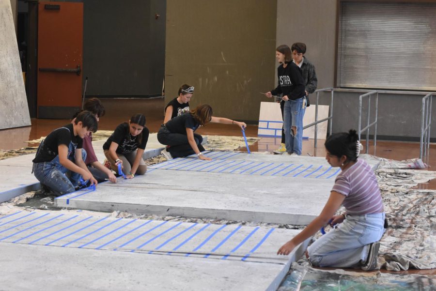 Students in Paint Crew work together to create brick walls for the Radium Girls set. Radium Girls is a play based on the real Radium Girls of 1926, who worked in factories painting watch dials with luminous paint, unaware that it consisted of radium, a toxic chemical.