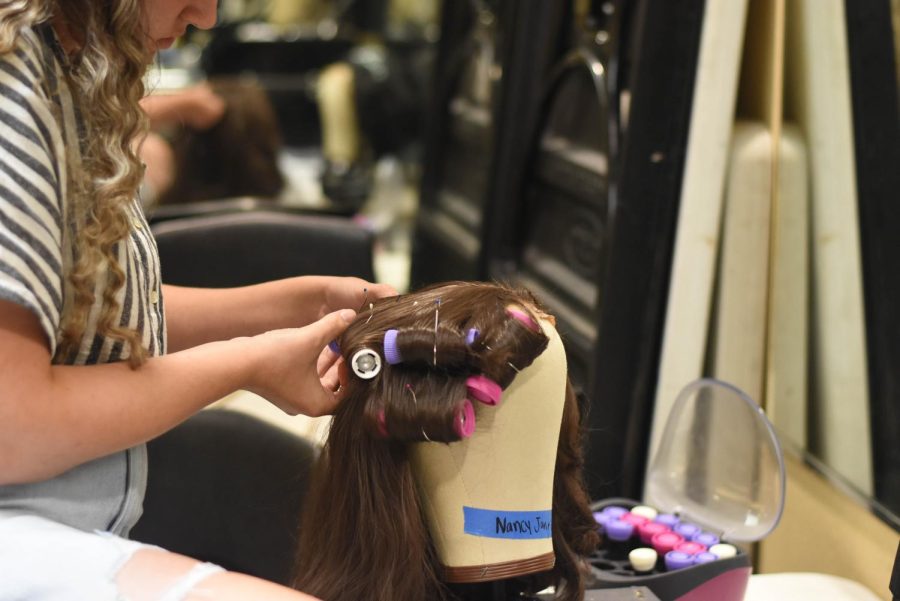 Junior Vanessa Roseli pins rollers onto a wig used in the production. 
