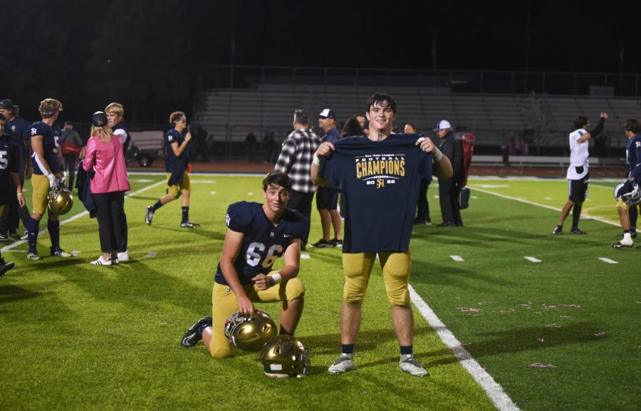 Cooper Javorsky (9) kneels next to Jake Javorsky (11) who holds up a Sea View League Championship shirt, celebrating the Stallions’ victory over Aliso Niguel High School. Despite an 0-7 start to the season, the SJHHS football team clinched the Sea View League Championship title as well as a spot in the CIF Playoffs.