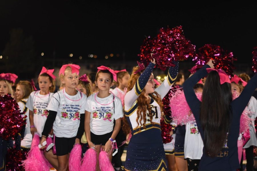 Varsity cheerleaders stand with aspiring young athletes, otherwise known as “Future Stallions,” who are given the opportunity to dance alongside current Stallion cheerleaders and experience a highschool football game every year.