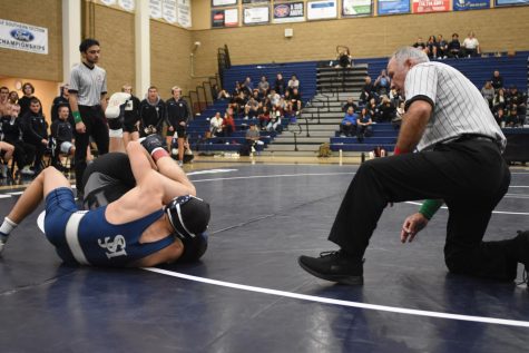 Takedown: The referee watches as a Stallion cradles a Trabucco Mustang at a dual meet. The wrestling team was established this year, and since then multiple athletes made it to CIF, and Jake Topartzer made it to the Masters tournament.