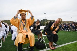 Moments before graduation caps flew into the sky, Scholar of Scholars, Kent Lau, moves his tassel to one side as AP Psych teacher looks on.