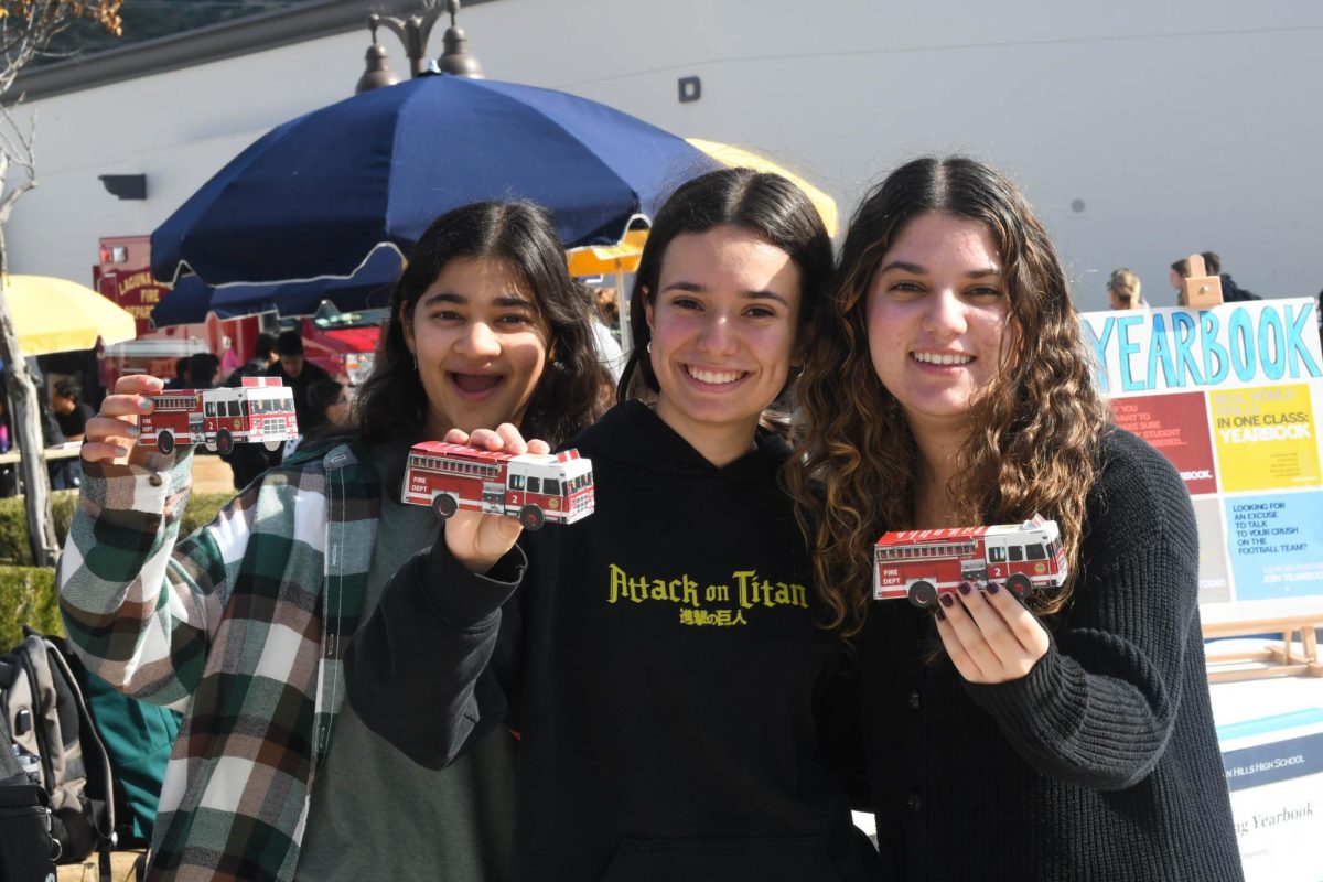 Elana Banduk (11), Sadeen Hindiyeh (12), and Isabella Bello (11) stand together holding paper firetrucks they got to make at the EMT stand during the Elective Fair on Tuesday. The Elective Fair allows students to learn more about the electives offered at San Juan Hills High School, preparing them to make decisions for their classes next year. 