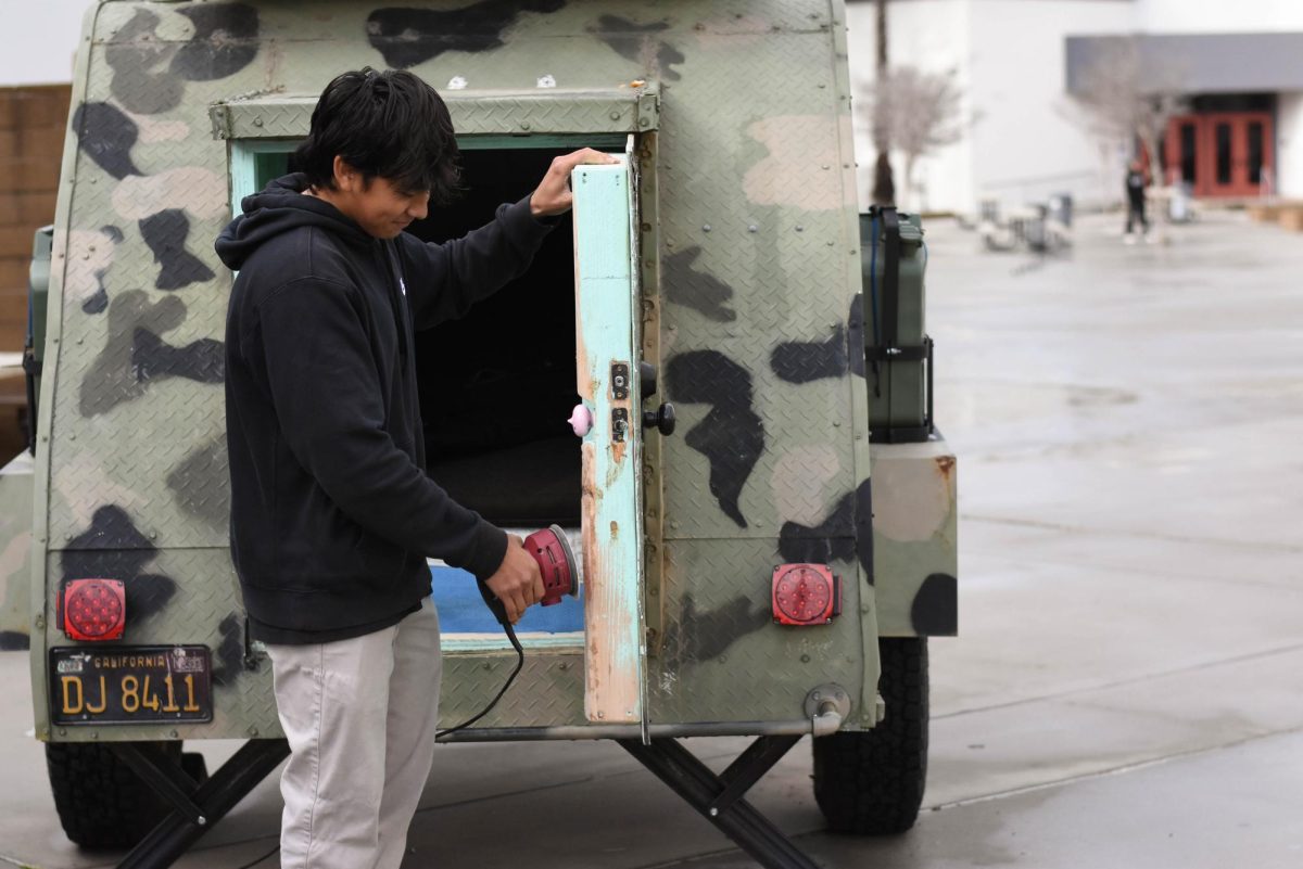 Tlatonani Loia sands down the door of a trailer to prepare it for a fresh paint job. Loia is apart of Building Industry Technology Academy (BITA), a class offered at SJJHS that teaches student practical building and technological skills.