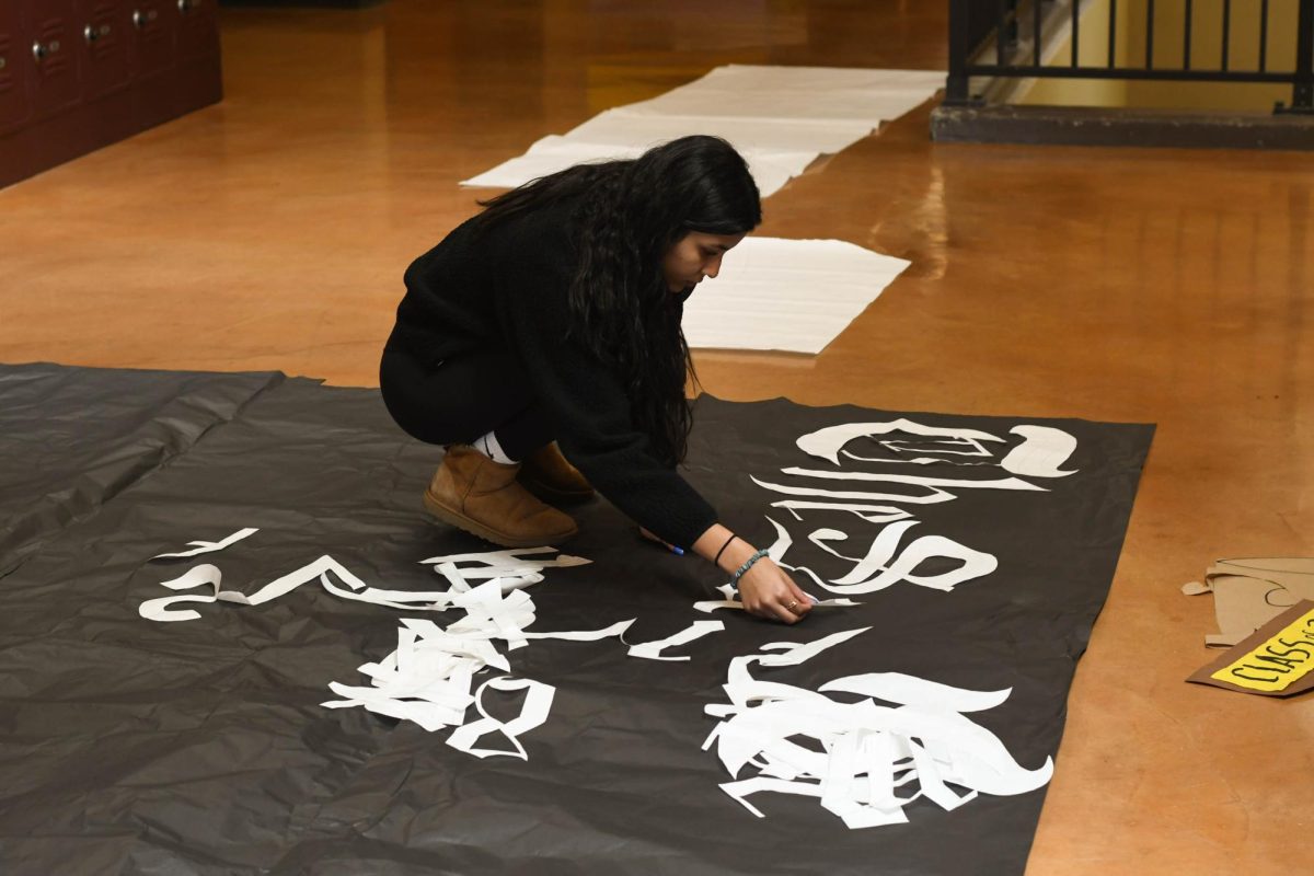 Meticulously crafting a New York Times inspired senior class poster, Commissioner of Publicity Anjali Mehra (12) prepares for Clash of the Classes. Creating posters inspired by brands that correspond with class colors is a longtime tradition of SJHHS’ annual Clash of the Classes.