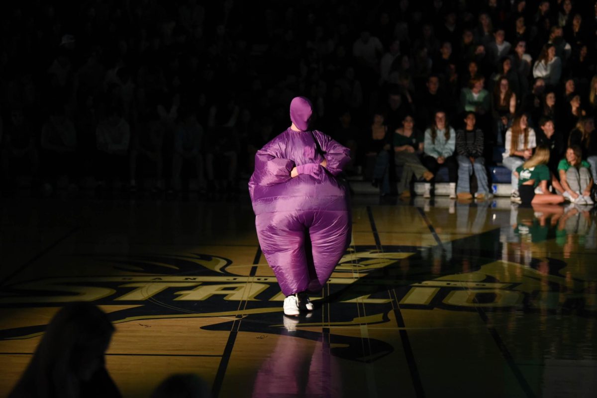 As the junior class video plays on the big screen, representing the color of the junior class, a purple inflatable rushes out onto the floor to cheer on the crowd.