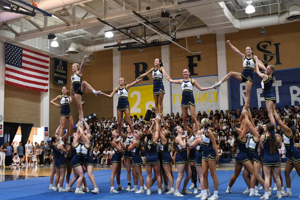 Showing off her impressive athleticism, center flyer Greta Wolfsohn (12) stuns in a pyramid stunt. For its first performance of the school year, Varsity Cheer puts on a high-energy and dynamic routine. 