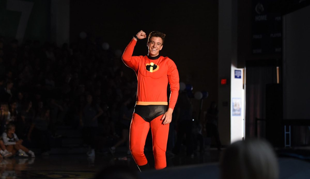 Pep rally MC Zack Smith (12) celebrates his win after a previous push-up contest with a randomly selected crowd member. He roamed around the center of the rally arena, glorifying his win and the Homecoming theme as Mr. Incredible.
