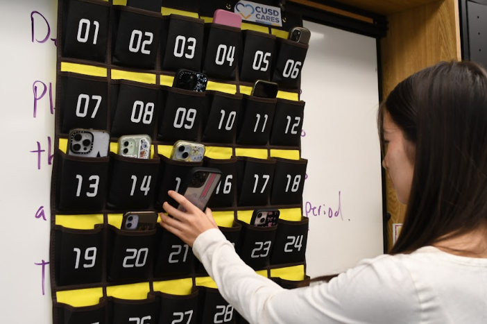 Rowan Noonan (12) places her phone into what students refer to as the “phone jail”. This system students must follow in all their classes is a new mandate put in place by the CAPO Unified School District.