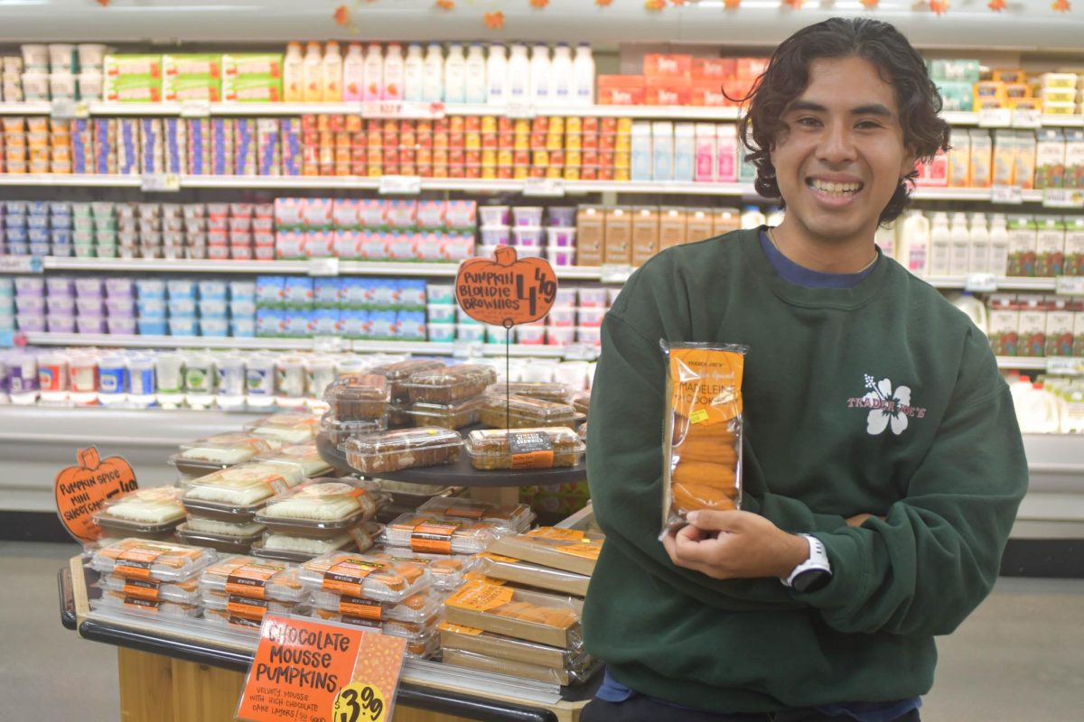 During his shift, a Trader Joe's employee stands, proudly displaying the pumpkin spiced madeline cookies. These cookies are one of many products at Trader Joe’s that are part of the new fall season foods.