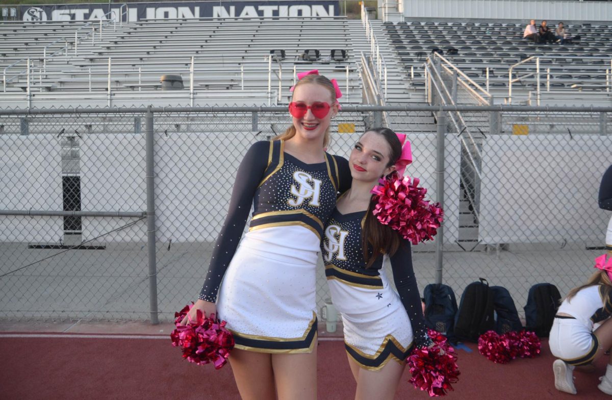  Posing with bright smiles, Frosh/Soph cheerleaders Summer Rice (10) and Alexandra McNutt (9) prepare to cheer on the Varsity Girls Flag Football team against Dana Hills. In honor of Breast Cancer Awareness Month, the cheerleaders are sporting pink bows and pink pom poms.