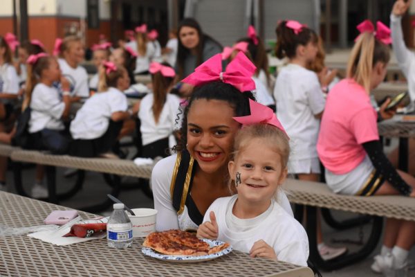 At the Future Stallion night for cheer and song, Ava Alaniz (9) spends time with a little stallion during their dinner break before performing at the football game. 