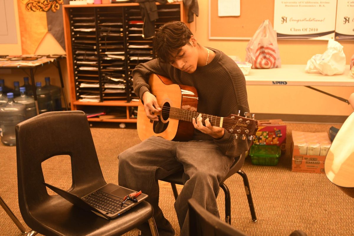 Learning new chords, Argeni Salinas focuses intently on mastering the guitar. He dedicates hours to refining his technique.