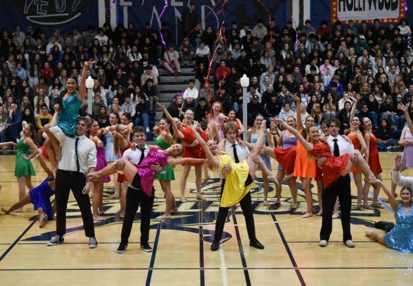 All the dancers pose together at the end of the pep rally finale dance, as confetti and streamers fly around. 
