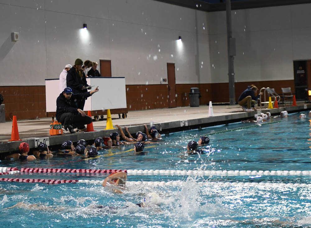 During half-time, Coach Rex Sample mentors girls water polo on how to win against Crean Lutheran. In the background, Crean Lutheran’s coach demonstrates the same behavior towards their team. The score was 9-12.