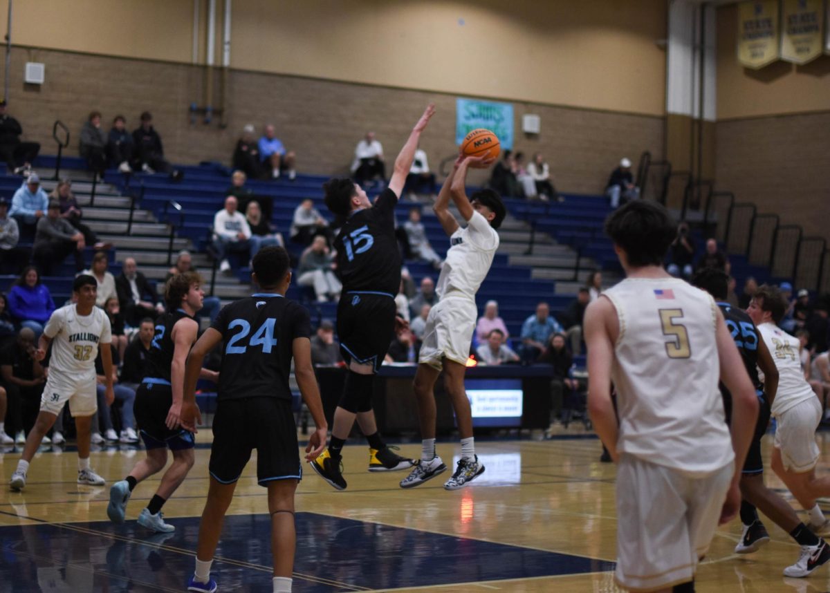 During the first league game for the boys varsity basketball team on January 10 against Dana Hills, Adam Aziz (12) jumps and shoots the ball toward the basket. Aziz got 14 points helping his team secure the 68-33 victory over the Dolphins. 