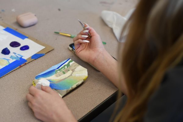 Sydney Garrick (12) works on her detailed painting of a landscape on a small carton. 