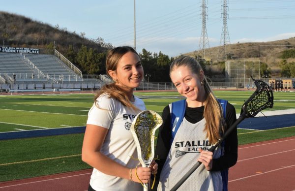  Preparing for practice, teammates Katelyn Johnson (11) and Kenna Maguire (11) display their friendship. Outside of school, the students play together on a club lacrosse team, working together on both teams to further their skills.