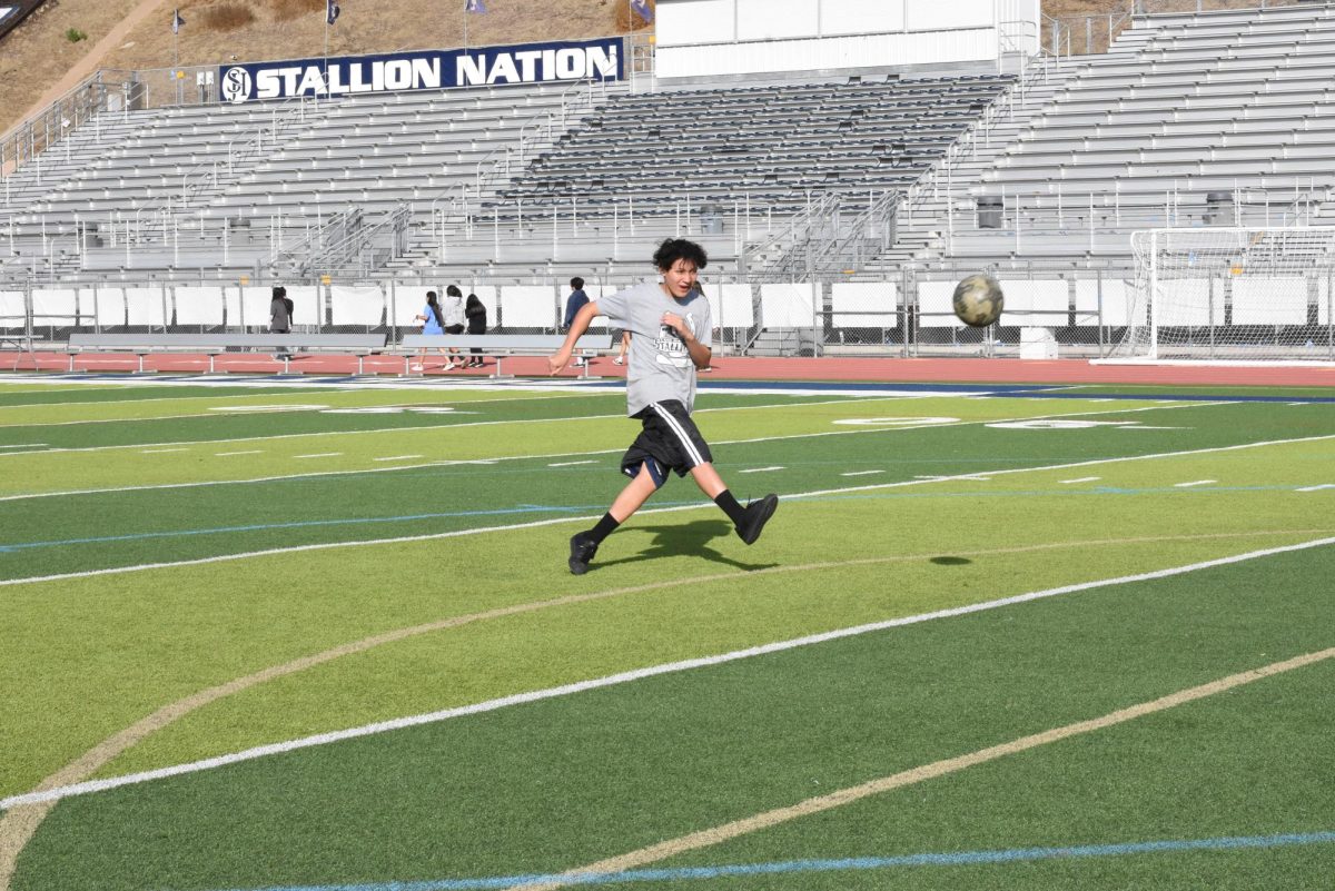 During first period Physical Education, Pablo Viveros (9) strikes the soccer ball toward the goal. During PE, students find fun ways to exercise.