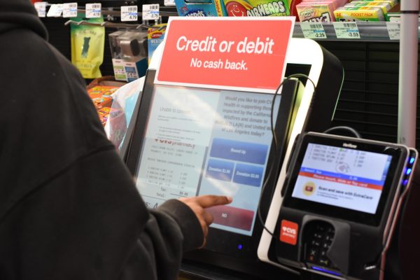  Zaleeya Dhalla standing at checkout screen, contemplating the option of leaving a tip. The screen displays a prompt for gratuity at the end of her purchase. 