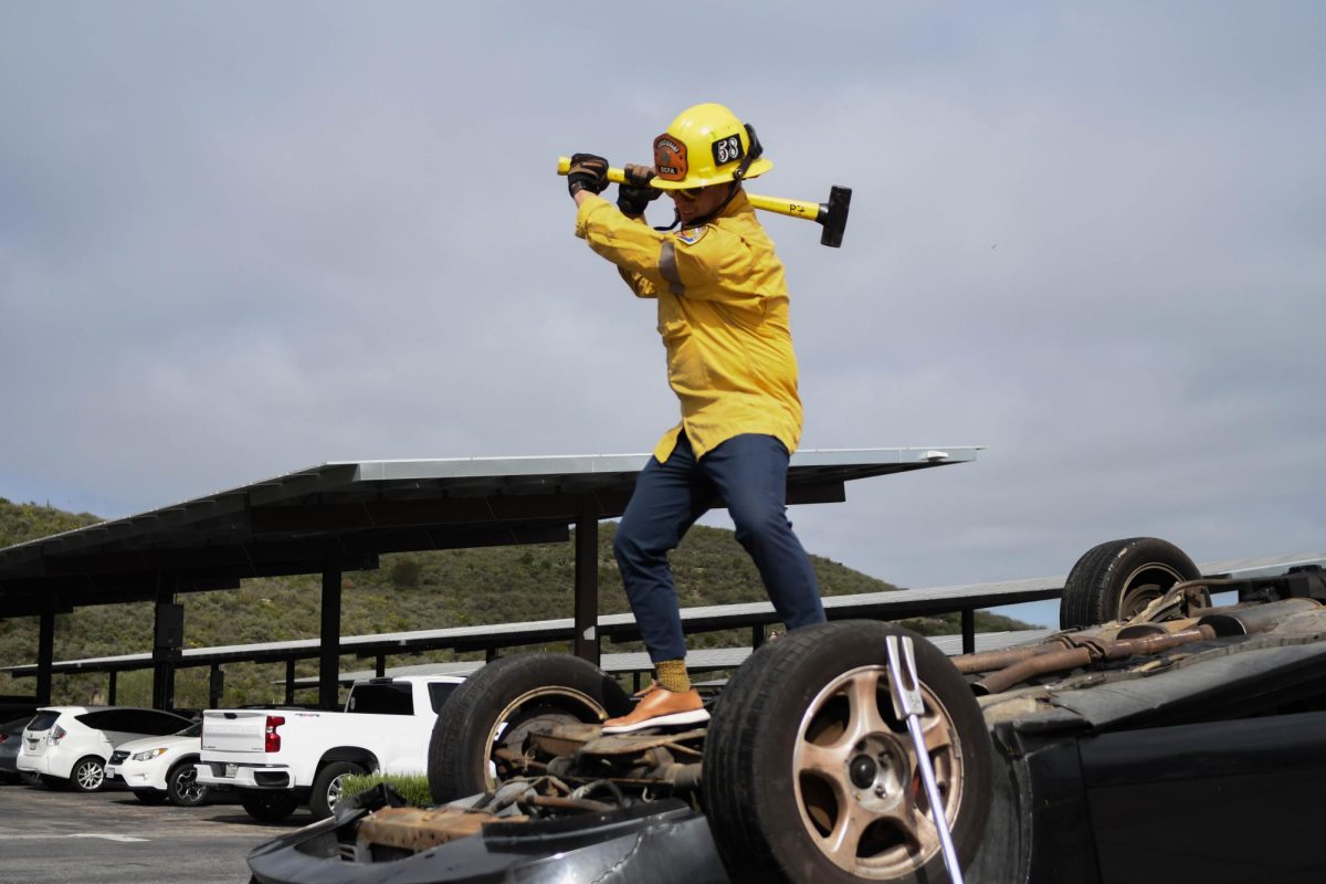 Principal Cina Abedzadeh dresses as a firefighter and takes an axe to one of the wrecked cars. Abedzadeh assisted in setting up the crash scene before the arrival of students. 