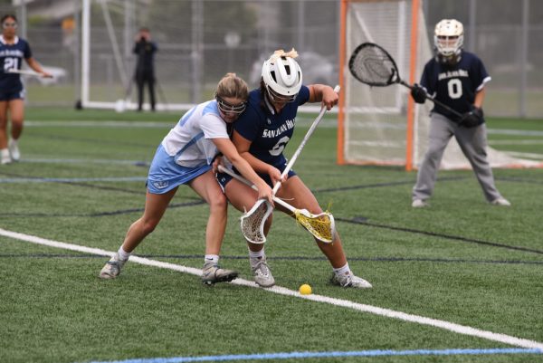 Girls varsity lacrosse player, Chloe Villicana (12), fights for the ground ball after Corona Del Mar high school overturns the game possession. SJHHS Girls lacrosse team ultimately won the game with an ending score of 10-8. 

