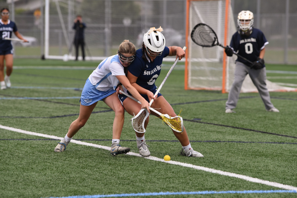 Girls varsity lacrosse player, Chloe Villicana (12), fights for the ground ball after Corona Del Mar high school overturns the game possession. SJHHS Girls lacrosse team ultimately won the game with an ending score of 10-8. 
