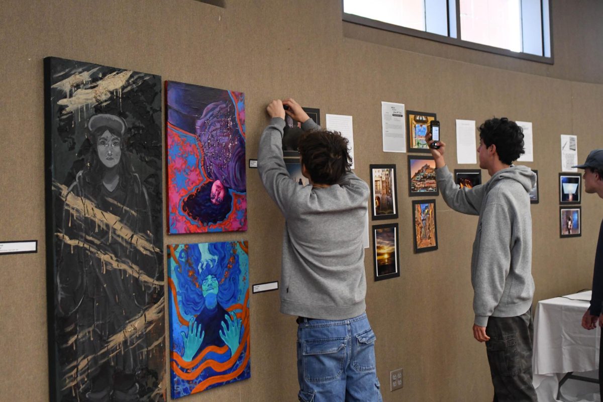 AP 2D Art and Design sets up their photographs and graphics for the art gallery hosted in the theater conference room. The art show showcases ceramics 1 and 2, AP 3D Art and Design, AP 2D Art and Design, and AP Drawing.