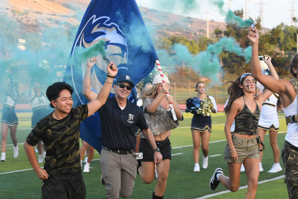 In a cloud of blue smoke the Stallions proudly take the field. Principal Cina Abedzadeh and ASB members follow after the football team as the game starts.