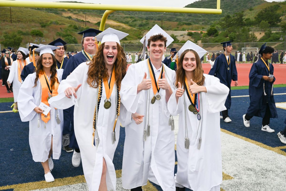 Graduates of the class of 2023 enter the stadium in the white robes designated for Valedictorians.
