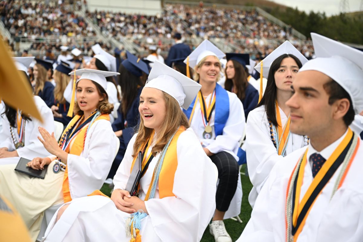 Graduates of the class of 2023 sit in the stadium in their white robes designated for Valedictorians.